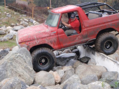 1978 Ford Bronco - A red 1978 Ford Bronco is shown off-roading over a rocky terrain.