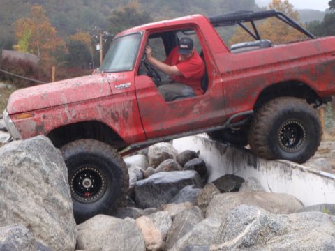1978 Ford Bronco - A red 1978 Ford Bronco is shown off-roading over a rocky terrain.