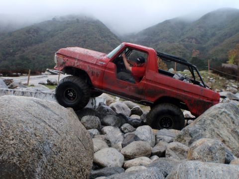 1978 Ford Bronco - A red 1978 Ford Bronco navigates a challenging rocky terrain, its off-road capabilities.
