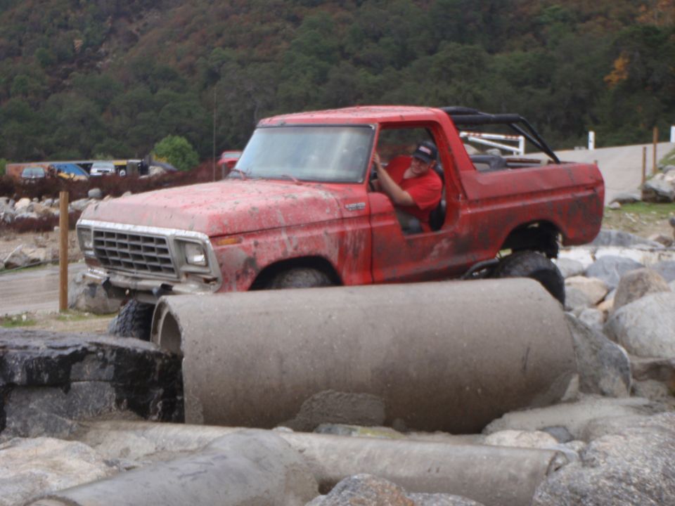 Red 1978 Ford Bronco navigating concrete pipes off-road