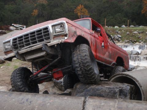 1978 Ford Bronco - This modified SUV is navigating a challenging obstacle course with large concrete pipes and rocks.