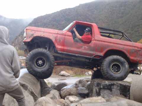 1978 Ford Bronco - This modified SUV is navigating a rocky obstacle course with a person watching.