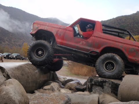 1978 Ford Bronco - A red 1978 Ford Bronco is shown off-roading over a rocky terrain.