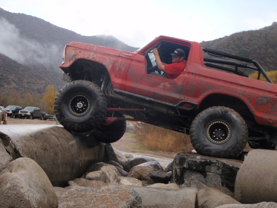 Red 1978 Ford Bronco with large tires navigating rocks