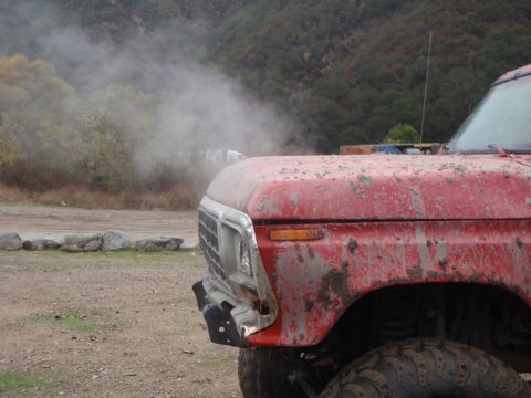 1978 Ford Bronco - Mud-covered 1978 Ford Bronco emitting smoke from the engine compartment.