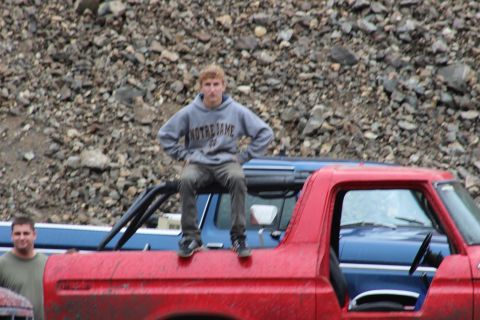 1978 Ford Bronco - A person sits atop a red pickup truck with another vehicle visible behind it.