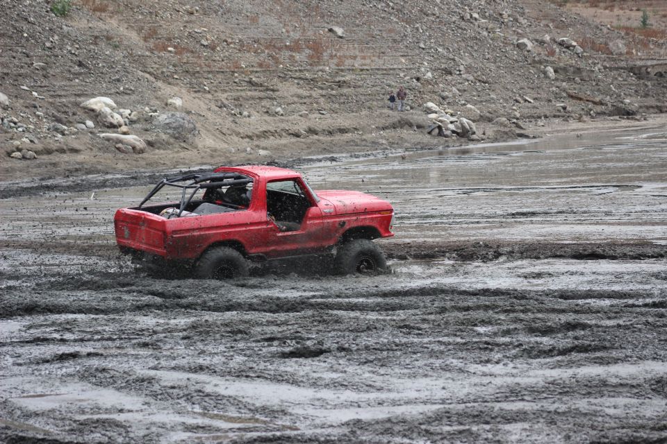 Red 1978 Ford Bronco driving through mud