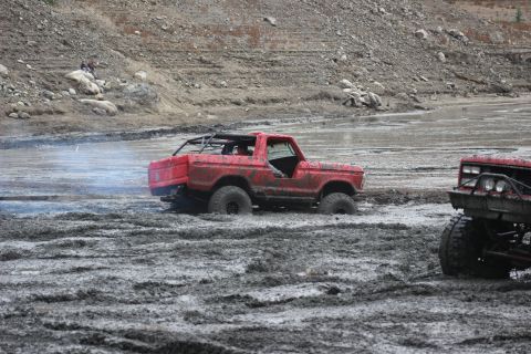 1978 Ford Bronco - Two off-road vehicles are stuck in thick mud, with one emitting smoke.