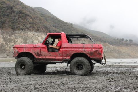 1978 Ford Bronco - 1978 Ford Bronco off-road in muddy terrain with a driver behind the wheel.