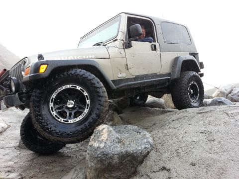 1978 Ford Bronco - A tan Jeep Wrangler Rubicon navigates a rocky terrain, demonstrating its off-road capabilities.