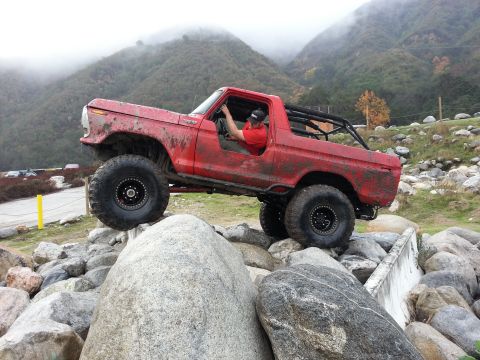 1978 Ford Bronco - This red 1978 Ford Bronco is shown off-roading over large rocks.