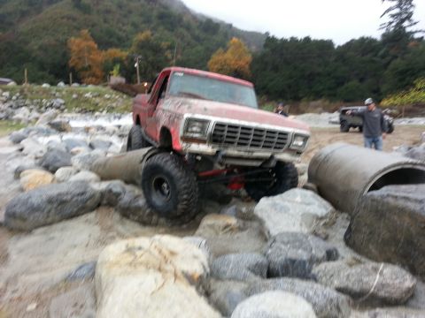 1978 Ford Bronco - A red 1978 Ford Bronco tackles a rocky obstacle course, with another vehicle visible in the background.