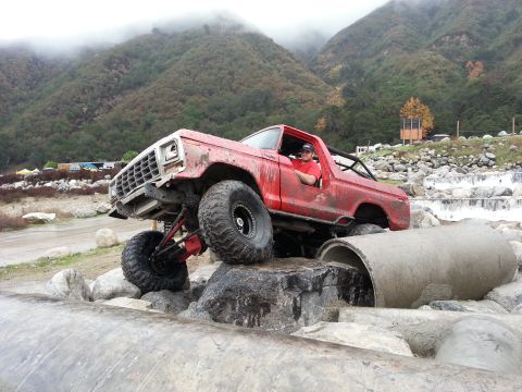1978 Ford Bronco - A red 1978 Ford Bronco navigates a challenging off-road course with large tires and a lifted suspension.