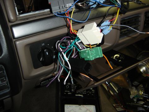 1996 Ford Bronco - The dashboard of a vehicle is disassembled, revealing complex wiring and a multimeter for testing.