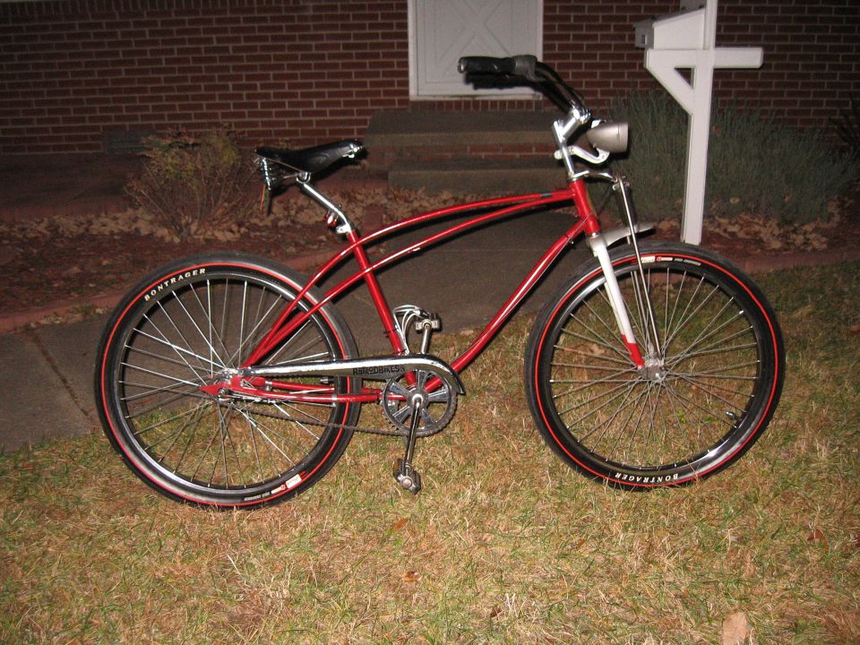 Red cruiser bicycle with chrome accents and black tires with red sidewalls