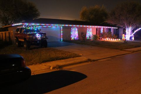 1990 Ford Bronco - A house and SUV are covered in Christmas lights at night.