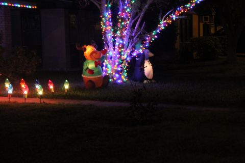1990 Ford Bronco - Outdoor Christmas decorations including inflatable figures and string lights illuminate a lawn at night.