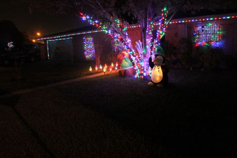 1990 Ford Bronco - A house is decorated for Christmas with lights and inflatable figures, creating a festive nighttime scene.