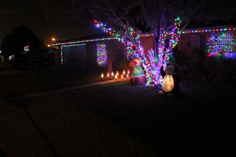 1990 Ford Bronco - A house is adorned with numerous Christmas lights, inflatable holiday figures on the lawn.
