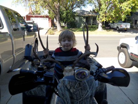 1994 Jeep Cherokee - A child poses with deer antlers while seated on an ATV, with vehicles visible in the driveway.
