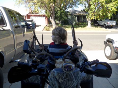 1994 Jeep Cherokee - Child with deer antlers on an ATV, with other vehicles parked nearby.