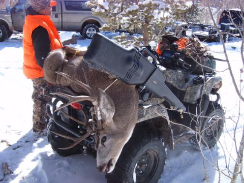 1994 Jeep Cherokee - A hunter stands next to a deer carcass loaded onto an ATV, with a pickup truck visible in the background.