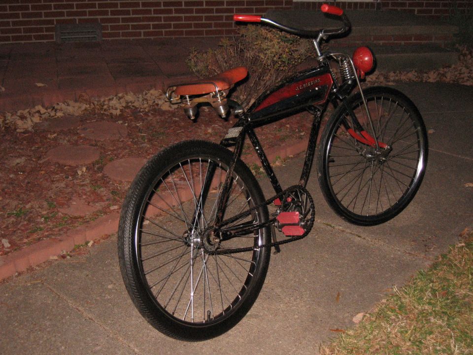 Black and red vintage bicycle with a brown seat and red handlebars