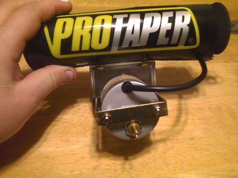 2003 Ford Crown Victoria - A ProTaper handlebar pad is shown mounted above a carburetor, with a hand holding the pad.