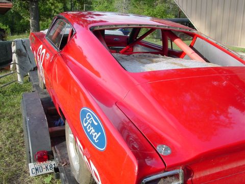 1968 Ford Torino - Red 1968 Ford Torino race car with roll cage, seen from the rear on a trailer.