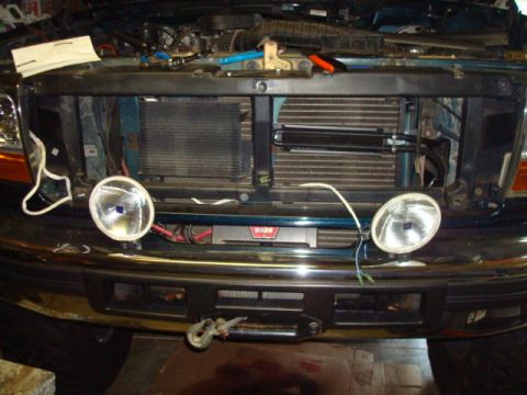 1995 Ford Bronco - Vehicle front end with hood open, revealing radiator and offroad lights mounted on the bumper.