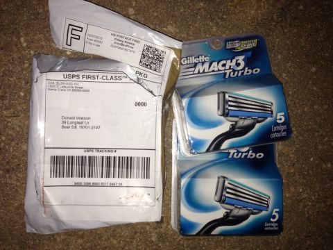 2000 Ford Crown Victoria - Two USPS packages and two packs of Gillette Mach3 Turbo razor cartridges are laid out on a textured surface.