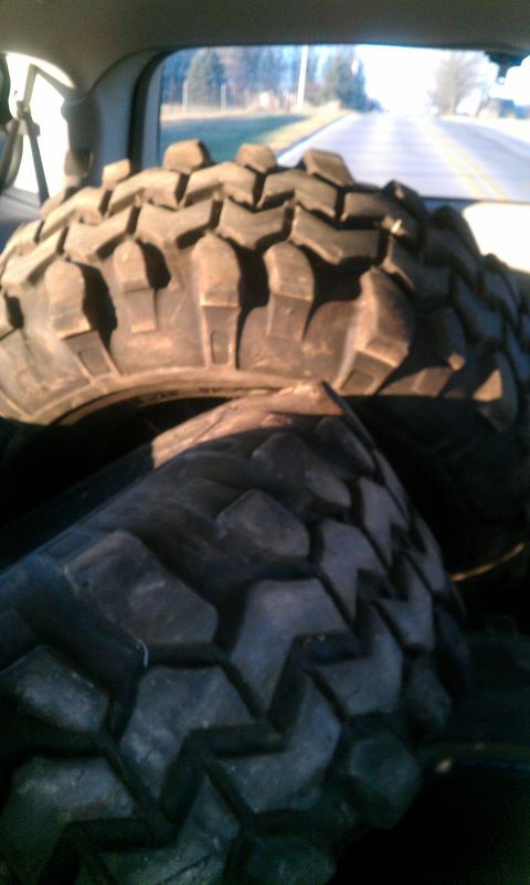 1995 Ford Bronco - Several large off-road tires are visible, stacked inside the cargo area of a vehicle.