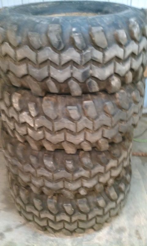 1995 Ford Bronco - A stack of four used off-road tires are piled up, showing their deep tread.