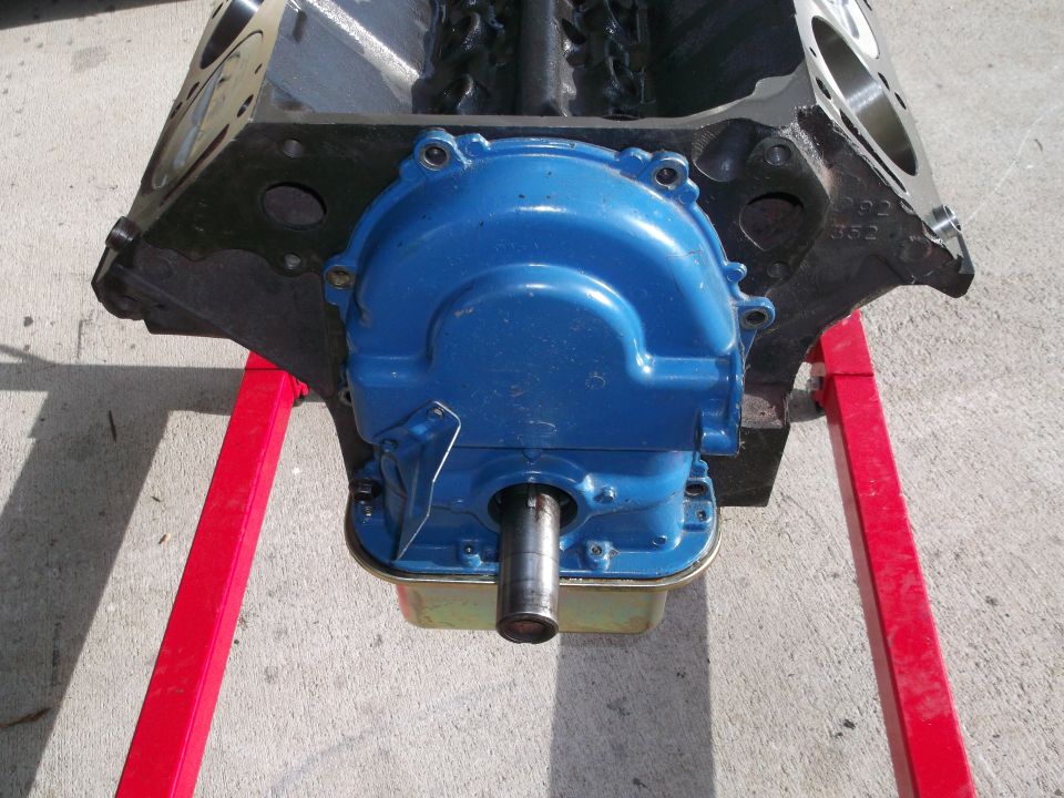 Engine block on red stands, showing a blue timing cover and crankshaft snout