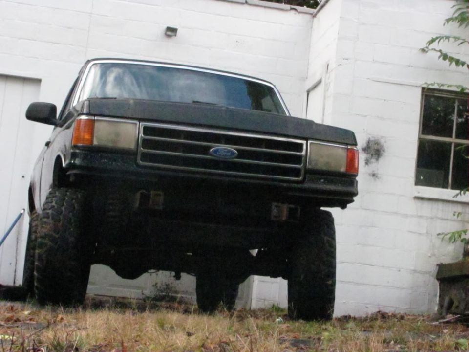 Dark-colored Ford F-150 pickup truck with lifted suspension, viewed from the front