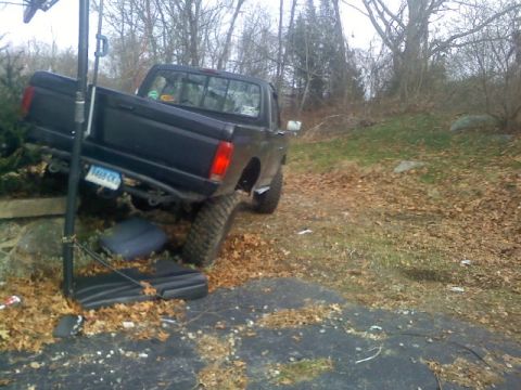 1994 Ford F-150 - A black pickup truck is parked at an angle on a dirt and leaf-covered area, with a basketball hoop pole nearby.