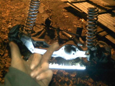 1994 Ford F-150 - A person holds up a hand in front of a disassembled truck rear axle assembly with springs.
