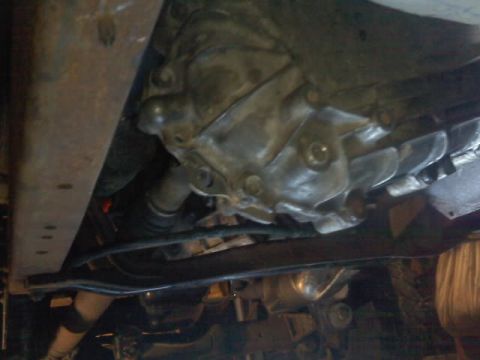 1994 Ford F-150 - A close-up view of the underside of a vehicle, focusing on the transmission and frame structure.
