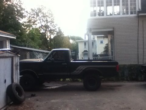 1994 Ford F-150 - A black pickup truck is parked in a driveway next to a shed and a house.