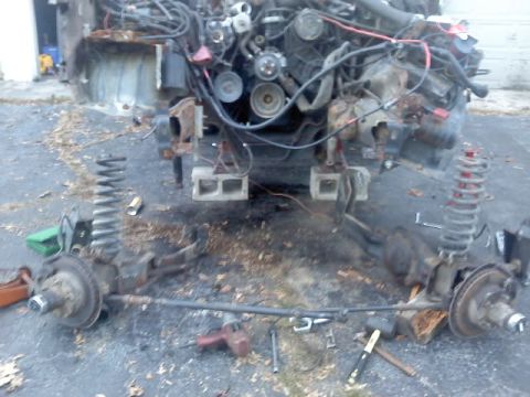 1994 Ford F-150 - Front suspension and engine assembly removed from a truck, lying on the ground.