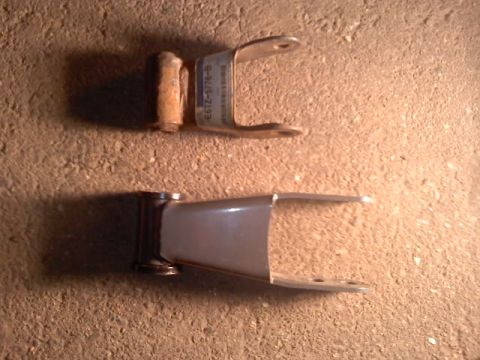 1994 Ford F-150 - Two leaf spring shackles and a bolt are shown on a textured surface.