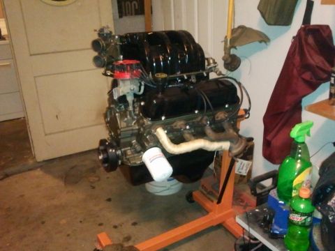 1990 Ford Bronco - Engine assembly displayed on an orange stand, a black intake manifold and red distributor cap.