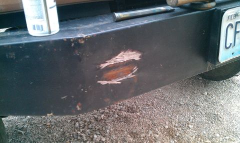 1987 Ford Bronco - Close-up of a damaged vehicle bumper with visible rust and a license plate.