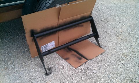 1987 Ford Bronco - A black push bar is shown being spray painted, supported by cardboard boxes.