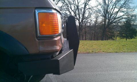 1987 Ford Bronco - Close-up of the front corner of a vehicle, showing the headlight and a custom push bar attachment.