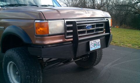 1987 Ford Bronco - A brown 1987 Ford Bronco is shown from the front, equipped with a custom black push bar.