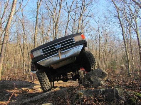 1994 Ford F-150 - Ford truck is shown off-roading on a rocky, wooded trail, with another vehicle in the background.