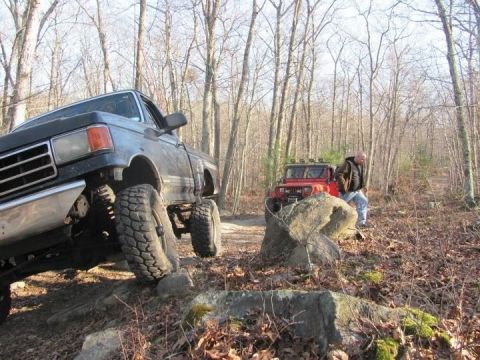 1994 Ford F-150 - A lifted 1994 Ford F-150 tackles a rocky path during an off-roading adventure, with another vehicle visible in the background.
