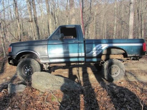 1994 Ford F-150 - This lifted 1994 Ford F-150 is navigating rocky terrain in a wooded area.