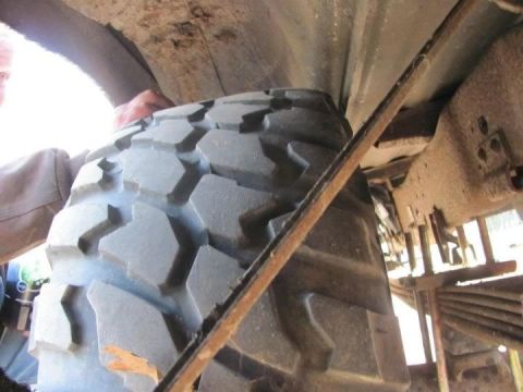 1994 Ford F-150 - Close-up view of a large tire and the vehicle's undercarriage, showing suspension and frame components.